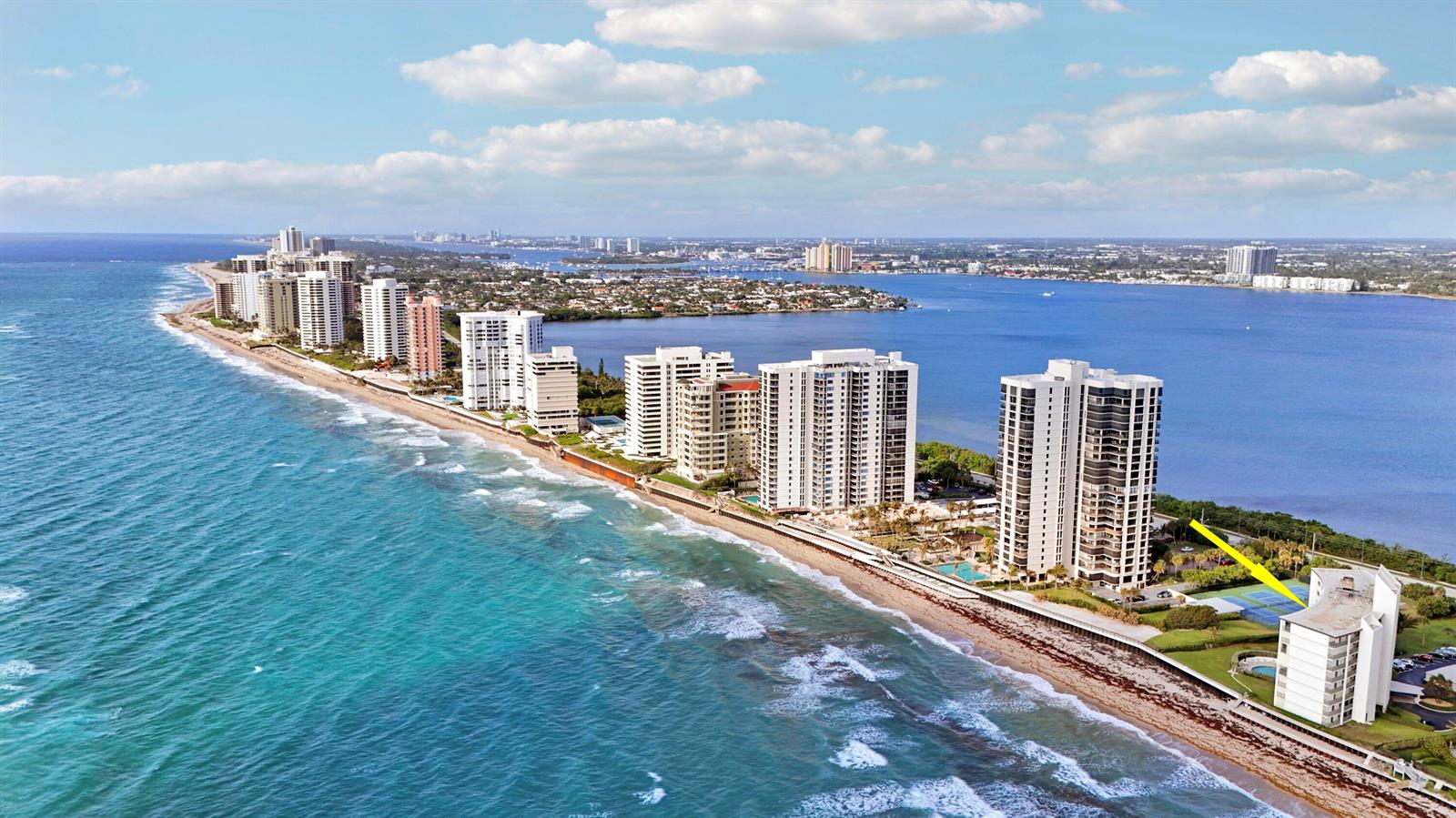 An aerial view of a coastal high-rise building with a yellow arrow pointing toward tennis courts — 5400 N Ocean Drive # 1b, Riviera Beach FL 33404, RIVIERA BEACH, FL
