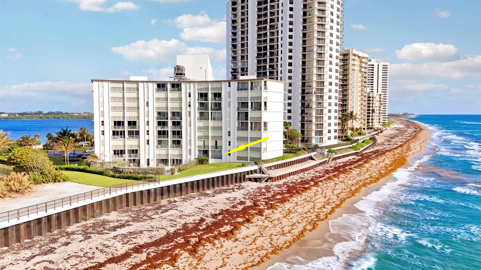 An aerial view of a beachfront condominium building with a yellow arrow pointing toward it — 5400 N Ocean Drive # 1b, Riviera Beach FL 33404, RIVIERA BEACH, FL