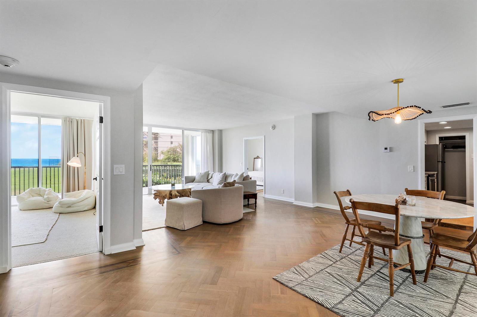 An open-concept living and dining area features herringbone wood floors and a view of the ocean — 5400 N Ocean Drive # 1b, Riviera Beach FL 33404, RIVIERA BEACH, FL