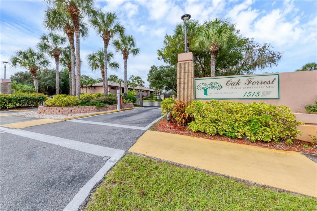 The entrance to a condominium complex features a gated driveway and a prominent community sign — 1515 FORREST NELSON BOULEVARD UNIT P105, PORT CHARLOTTE, FL