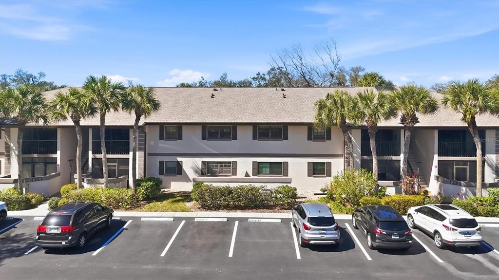 A two-story apartment building with a parking lot and palm trees in front — 1515 FORREST NELSON BOULEVARD UNIT P105, PORT CHARLOTTE, FL
