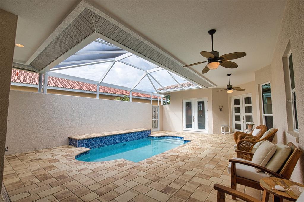 A covered patio features a small swimming pool, tiled decking, and two ceiling fans — 221 RIO TERRA, VENICE, FL