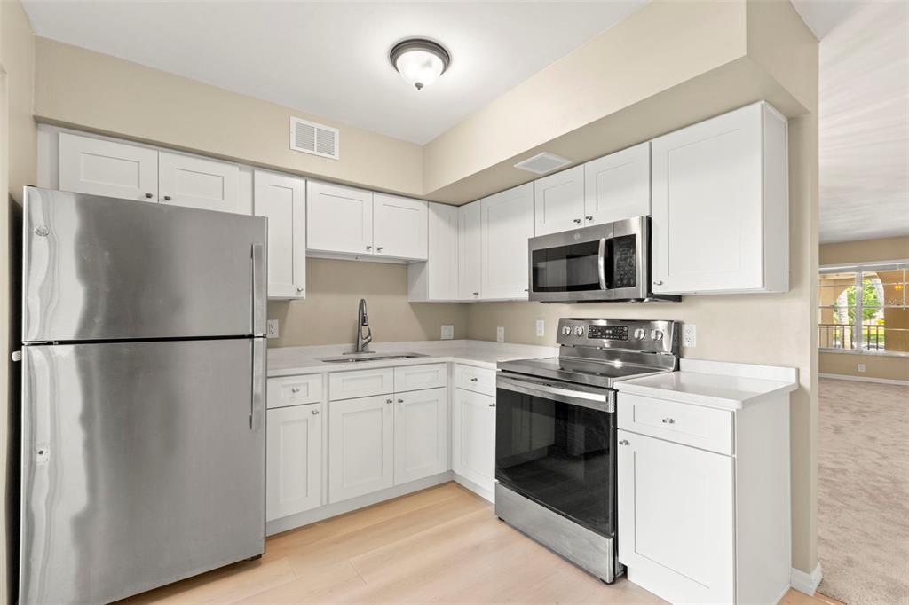 A kitchen features white cabinets, stainless steel appliances, and light-colored countertops — 2433 BRAZILIA DRIVE UNIT 41, CLEARWATER, FL