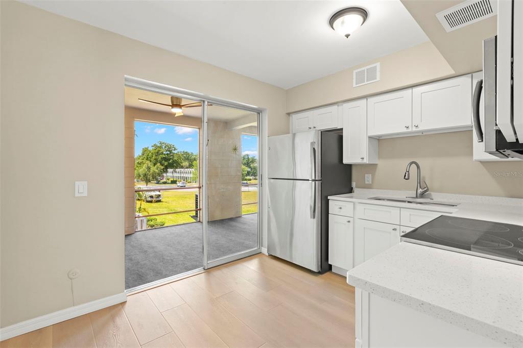 A kitchen with white cabinets, stainless steel appliances, and a sliding door to a patio — 2433 BRAZILIA DRIVE UNIT 41, CLEARWATER, FL