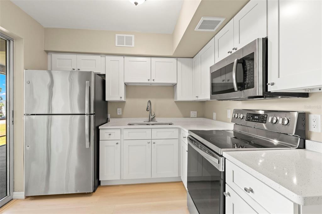 A kitchen features white cabinets, stainless steel appliances, and light-colored countertops — 2433 BRAZILIA DRIVE UNIT 41, CLEARWATER, FL