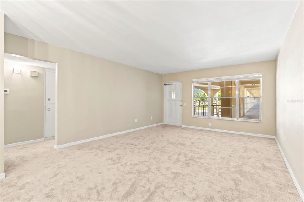 An empty living room with beige carpet, light-colored walls, and a white front door — 2433 BRAZILIA DRIVE UNIT 41, CLEARWATER, FL
