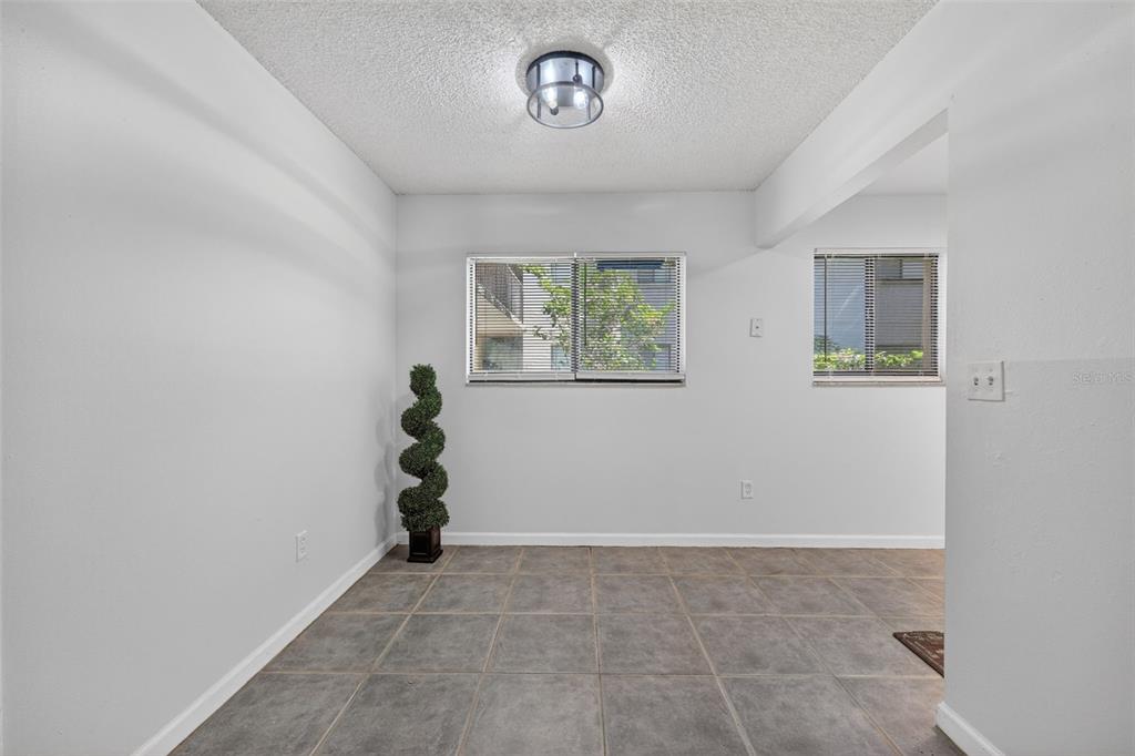 A room with gray tile flooring, white walls, a ceiling light, and two windows — 11715 RAINTREE VILLAGE BOULEVARD UNIT A, TEMPLE TERRACE, FL