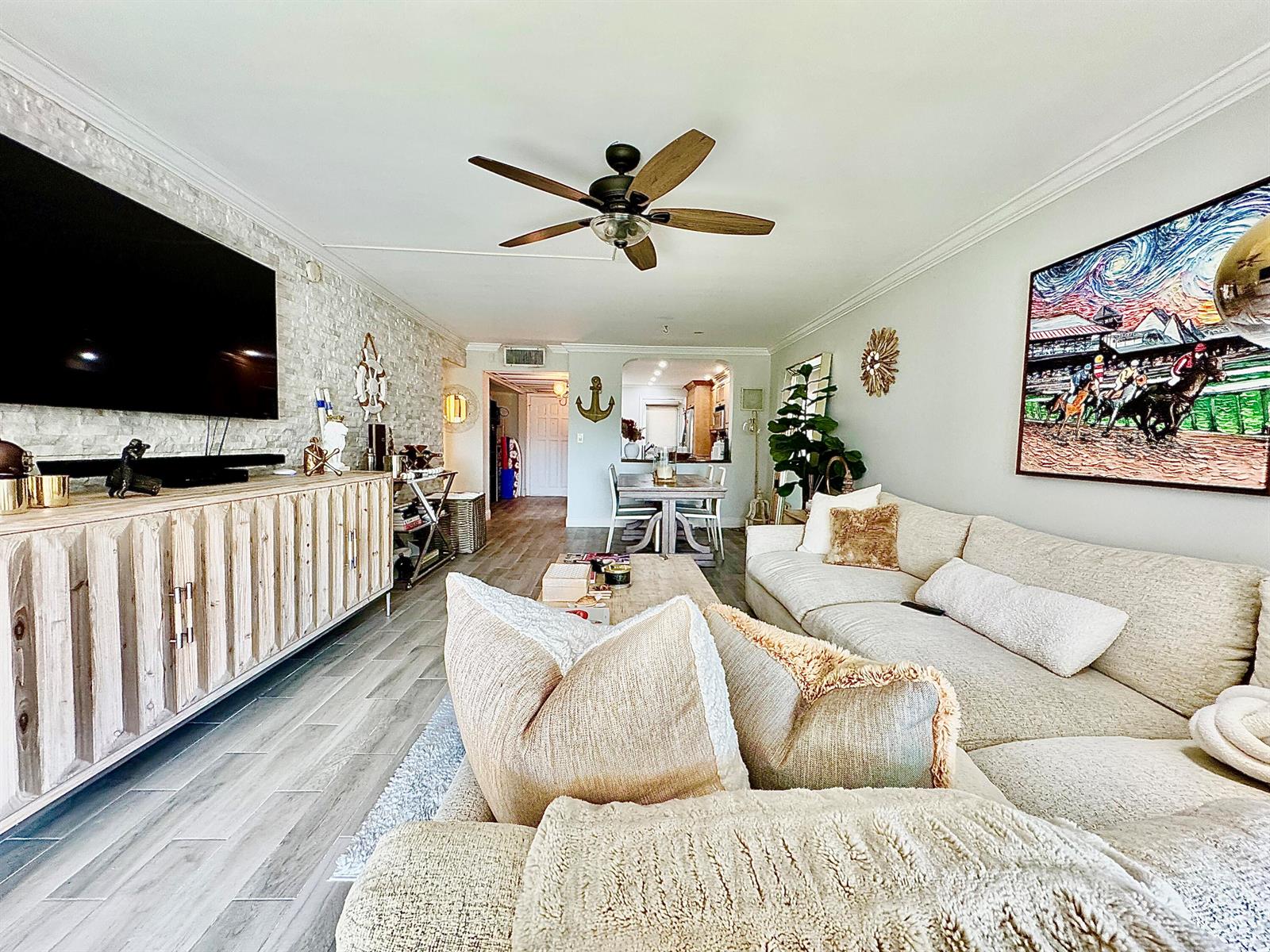 A living room features a stone accent wall, a large sectional sofa, and wood flooring — 2871 N Ocean Boulevard # R248, Boca Raton FL 33431, BOCA RATON, FL
