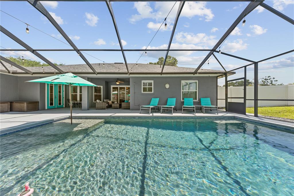 A swimming pool with a screened enclosure and lounge chairs on a patio — 1095 W LAKE HAMILTON DRIVE, WINTER HAVEN, FL