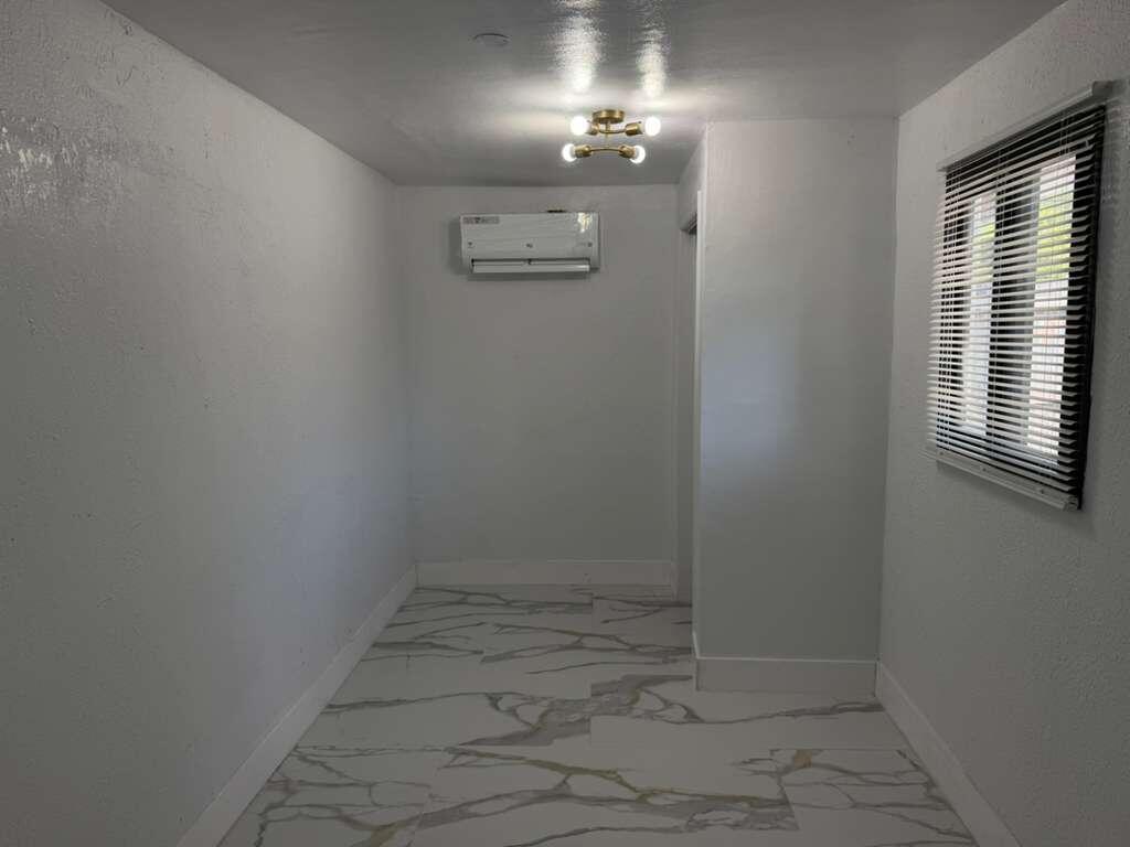 A small, empty room features white walls, a mini-split air conditioner, and marble-patterned tile flooring — 160 SE 15th Avenue Unit B, Pompano Beach FL 33060, POMPANO BEACH, FL