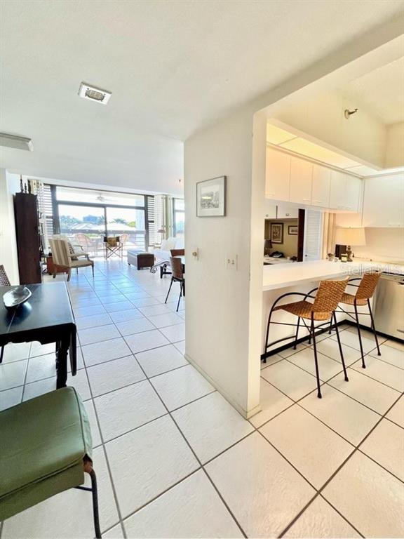 An open-concept living area features a kitchen with a breakfast bar and tiled flooring — 1065 GULF OF MEXICO DRIVE UNIT 302, LONGBOAT KEY, FL
