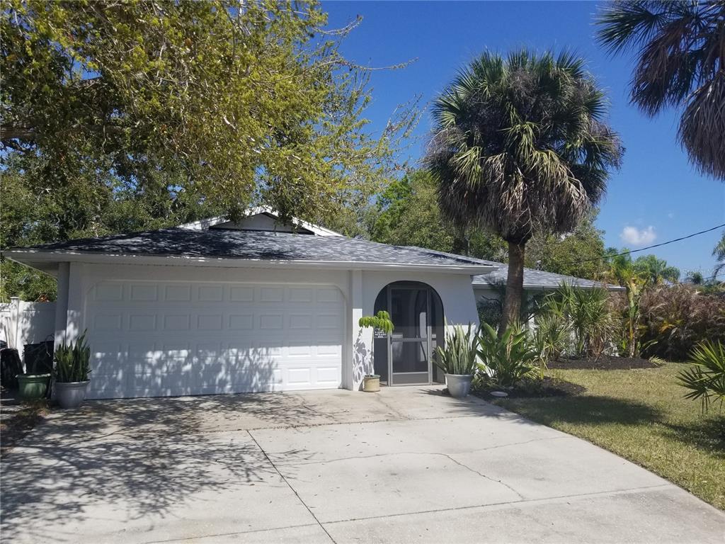 A single-story house with a white exterior, a two-car garage, and a palm tree — 1720 FOSSIL DRIVE, ENGLEWOOD, FL