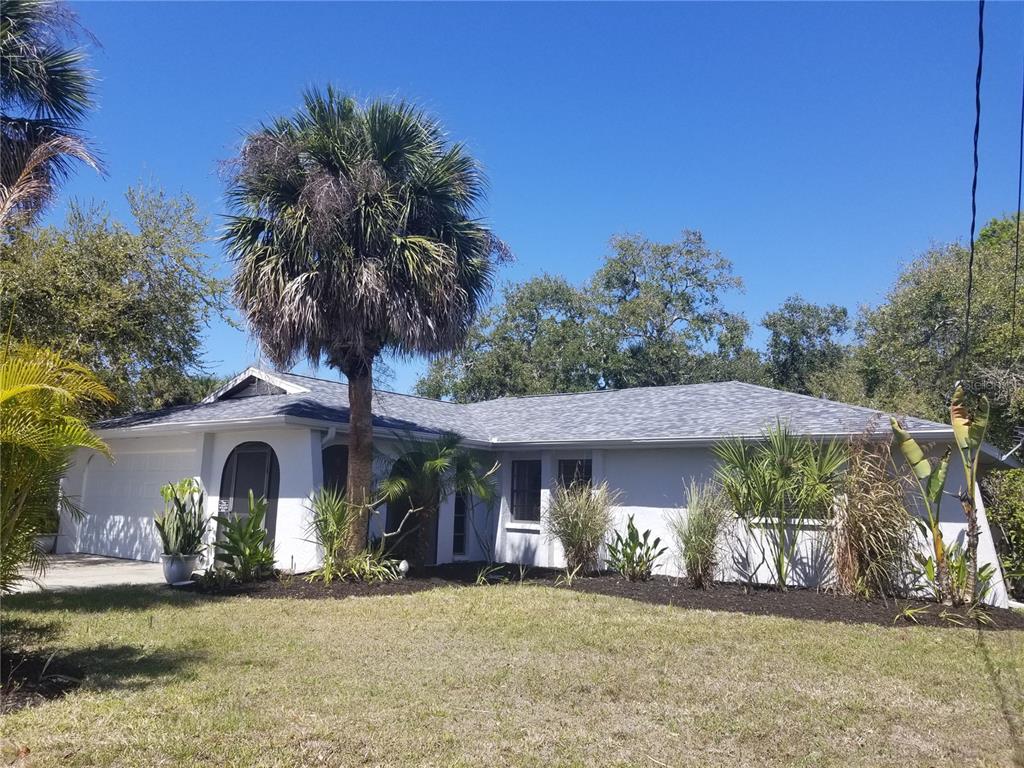 A single-story house with a gray roof, white exterior, and a prominent palm tree — 1720 FOSSIL DRIVE, ENGLEWOOD, FL