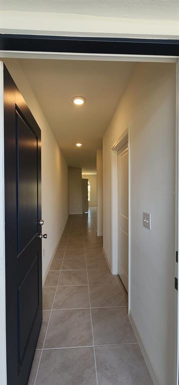 A view down a tiled hallway from an open doorway with a dark blue door — 1604 MIRABELLA CIRCLE, DAVENPORT, FL