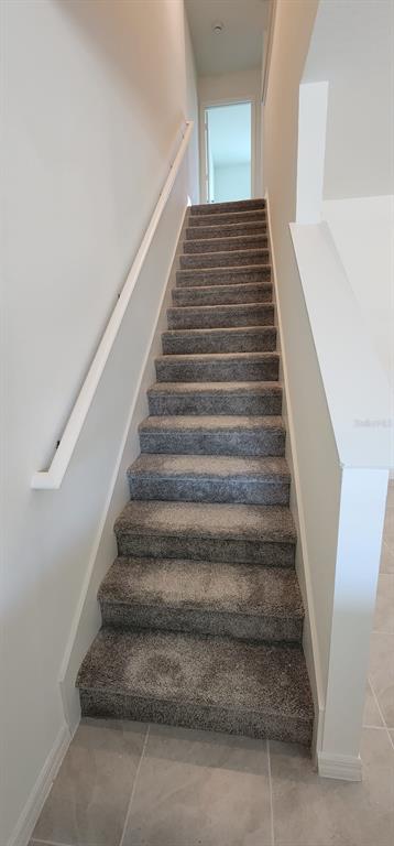 A straight staircase with gray carpeted steps and a white handrail leads to a landing — 1604 MIRABELLA CIRCLE, DAVENPORT, FL