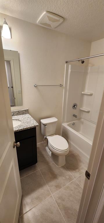 A bathroom features a dark vanity with a granite countertop, a toilet, and a tub-shower — 1604 MIRABELLA CIRCLE, DAVENPORT, FL