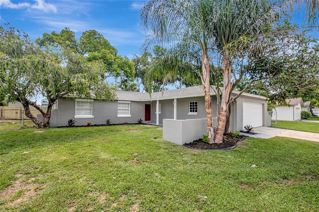 A single-story gray house with a white garage door and a palm tree in front — 917 WINCHESTER COURT, BRANDON, FL