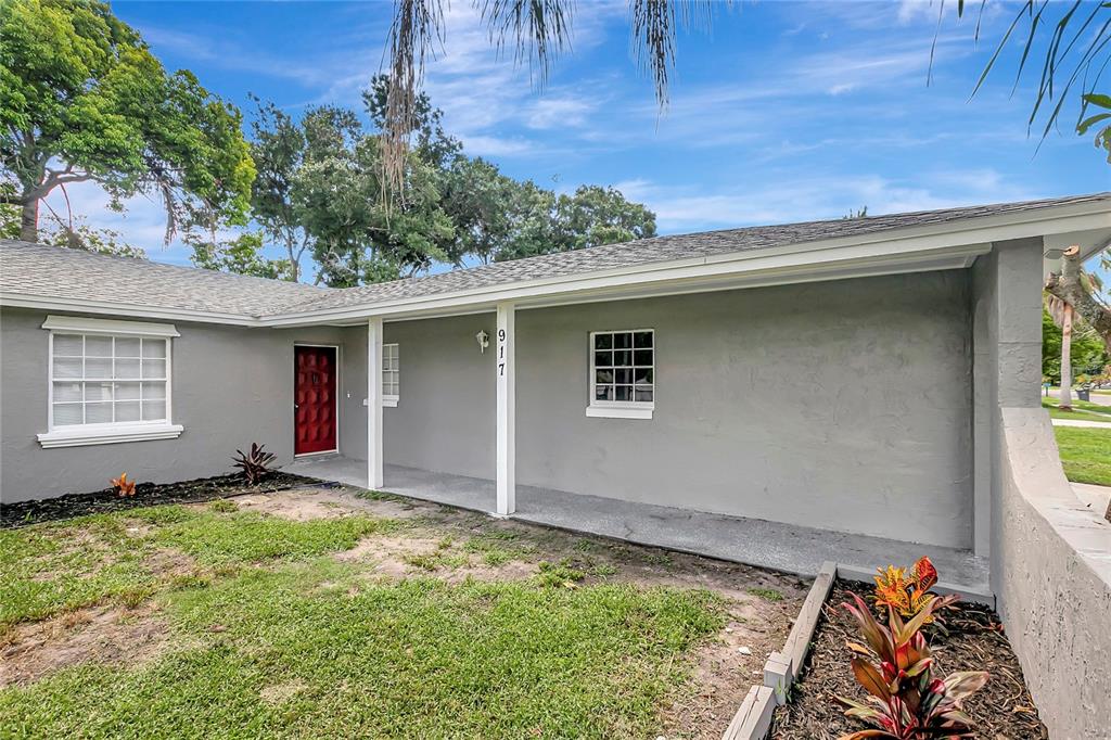 A gray single-story house exterior features a covered porch, a red door, and landscaping — 917 WINCHESTER COURT, BRANDON, FL