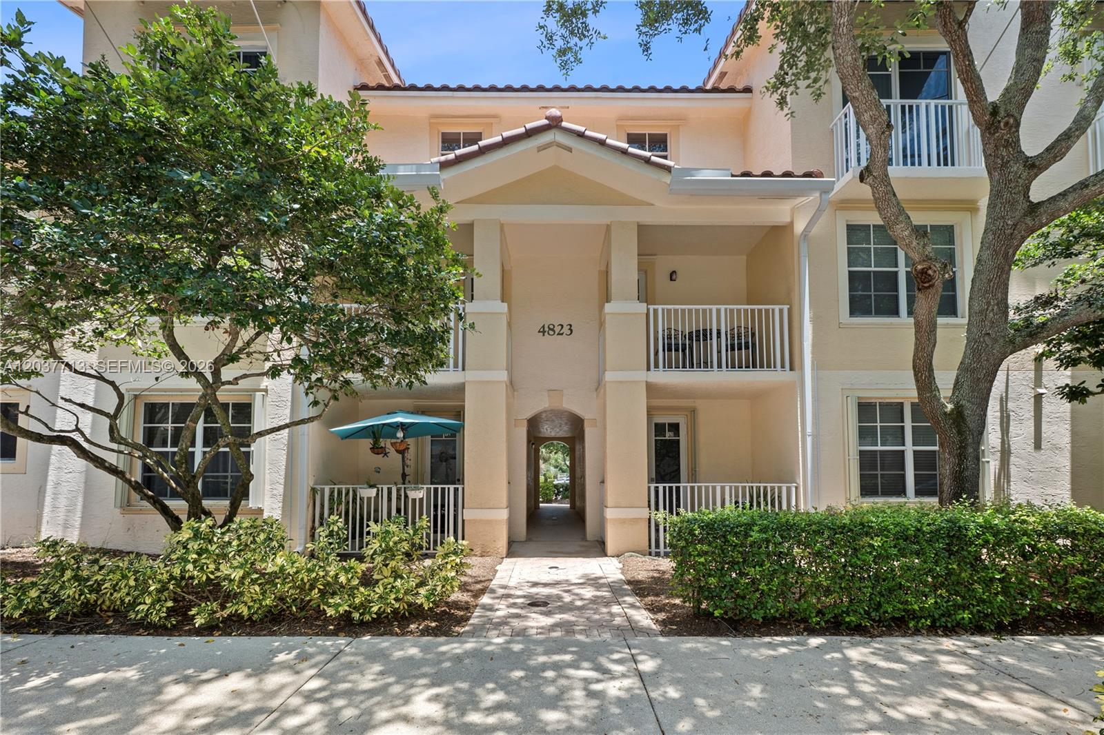 A multi-story apartment building exterior features a central arched walkway and balconies with white railings — 4823 Chancellor Dr # 22, Jupiter FL 33458, JUPITER, FL