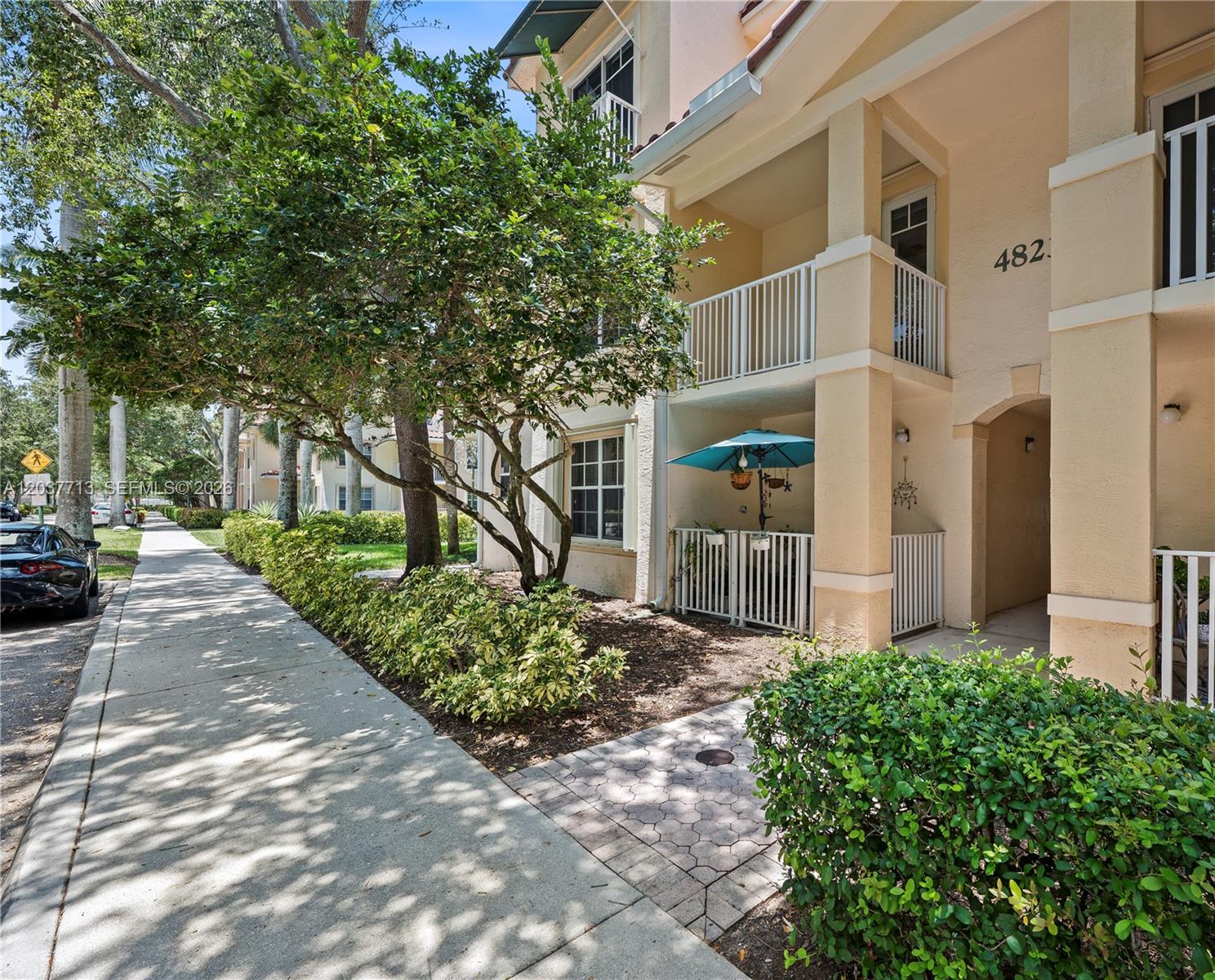 A two-story building exterior features a ground-floor patio with a blue umbrella and balcony above — 4823 Chancellor Dr # 22, Jupiter FL 33458, JUPITER, FL