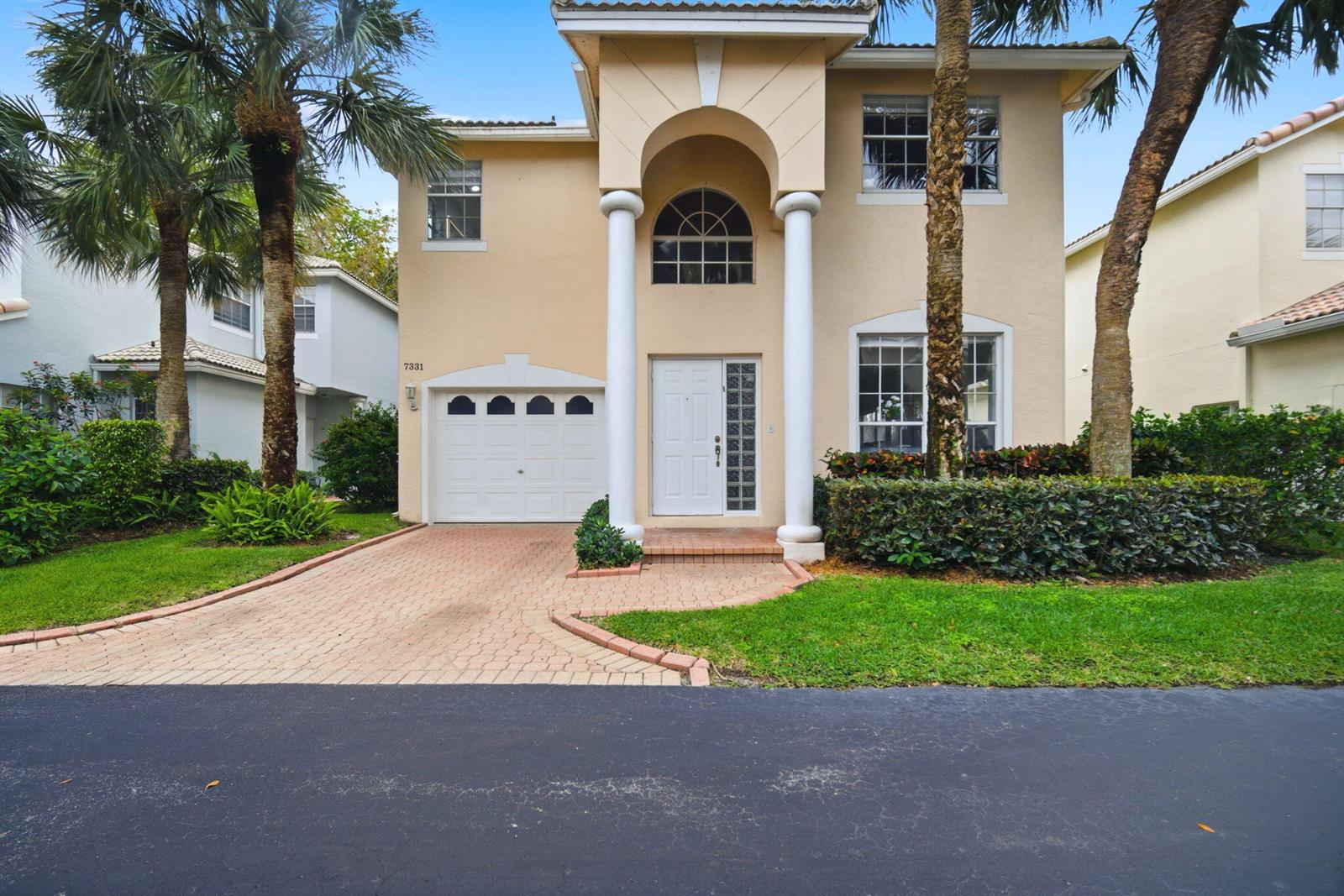 A two-story beige house features a white garage, arched entryway with columns, and palm trees — 7331 Panache Way, Boca Raton FL 33433, BOCA RATON, FL