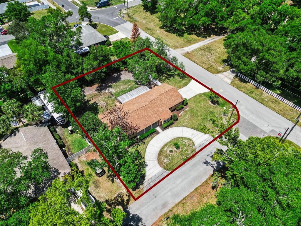 An aerial view shows a single-story house with a circular driveway on a corner lot — 80 WHITCOMB AVENUE, UMATILLA, FL