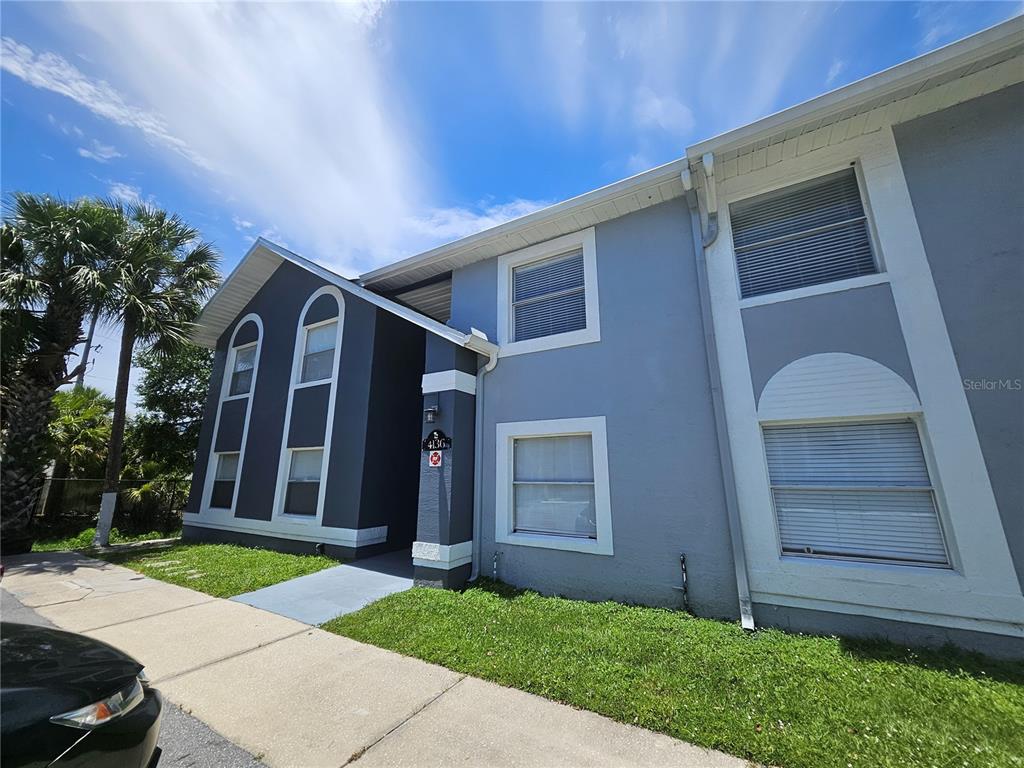 A two-story residential building exterior with gray stucco walls and white trim under a blue sky — 4136 PERSHING POINTE PLACE UNIT 4, ORLANDO, FL