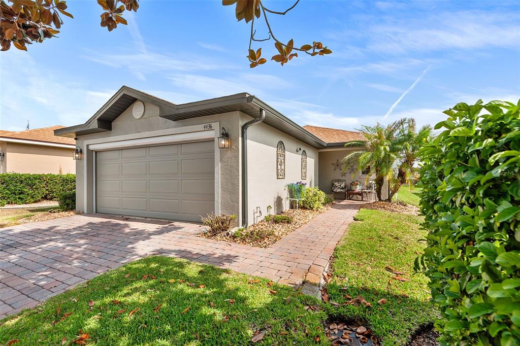 A single-story house with a beige stucco exterior, a two-car garage, and a brick walkway — 4436 TURNBERRY LANE, LAKE WALES, FL