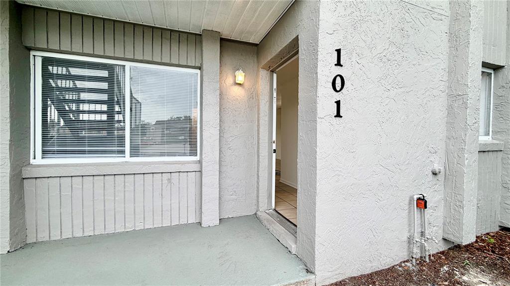 The exterior entrance of a ground-level unit features a gray concrete porch and door 101 — 101 CORY LANE, WINTER SPRINGS, FL