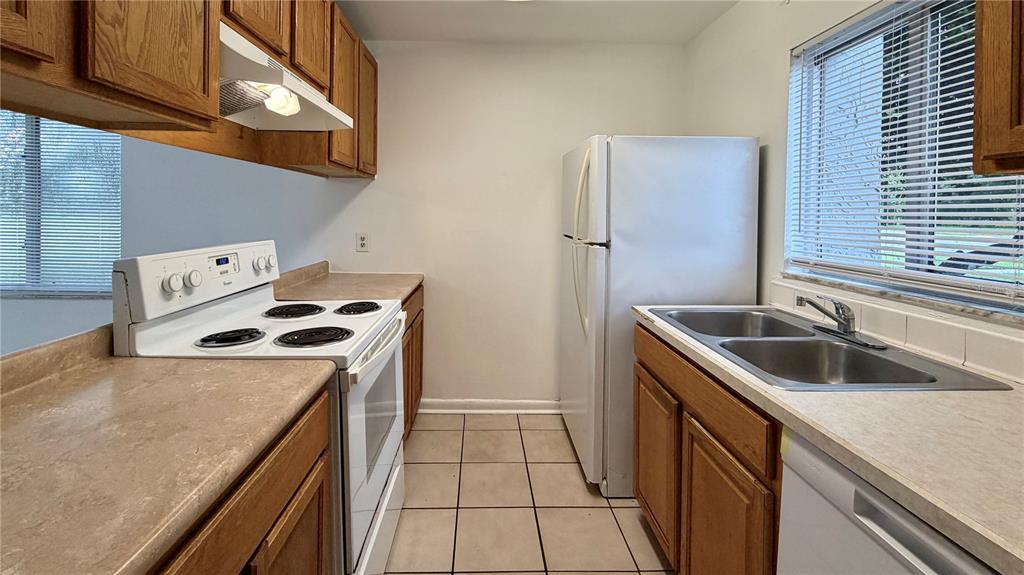 A kitchen features wood cabinets, laminate countertops, white appliances, and a double-basin stainless steel sink — 101 CORY LANE, WINTER SPRINGS, FL