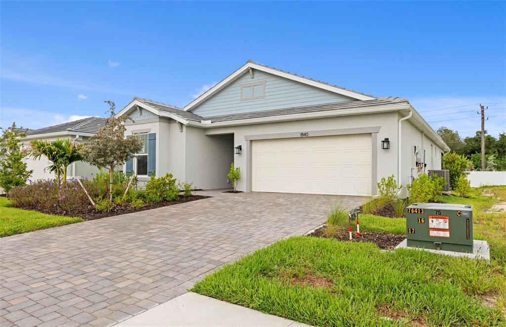 A single-story house with a light-colored stucco exterior, a two-car garage, and a paved driveway — 1840 SILVER SHORES BOULEVARD, ENGLEWOOD, FL