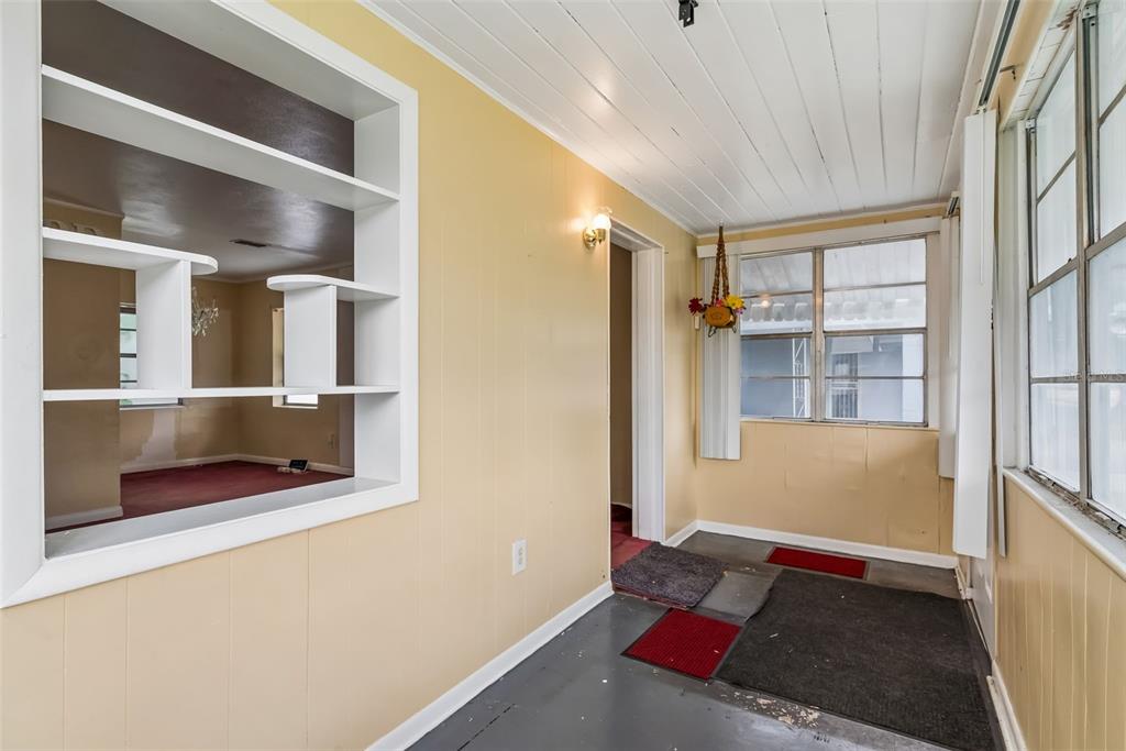 A sunroom with yellow paneled walls, a white ceiling, and a built-in shelving unit — 918 S GOLDWYN AVENUE, ORLANDO, FL