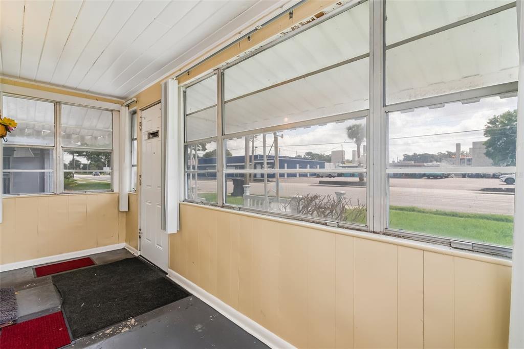 An enclosed porch features light-colored wood paneling, large windows, and a dark painted floor — 918 S GOLDWYN AVENUE, ORLANDO, FL