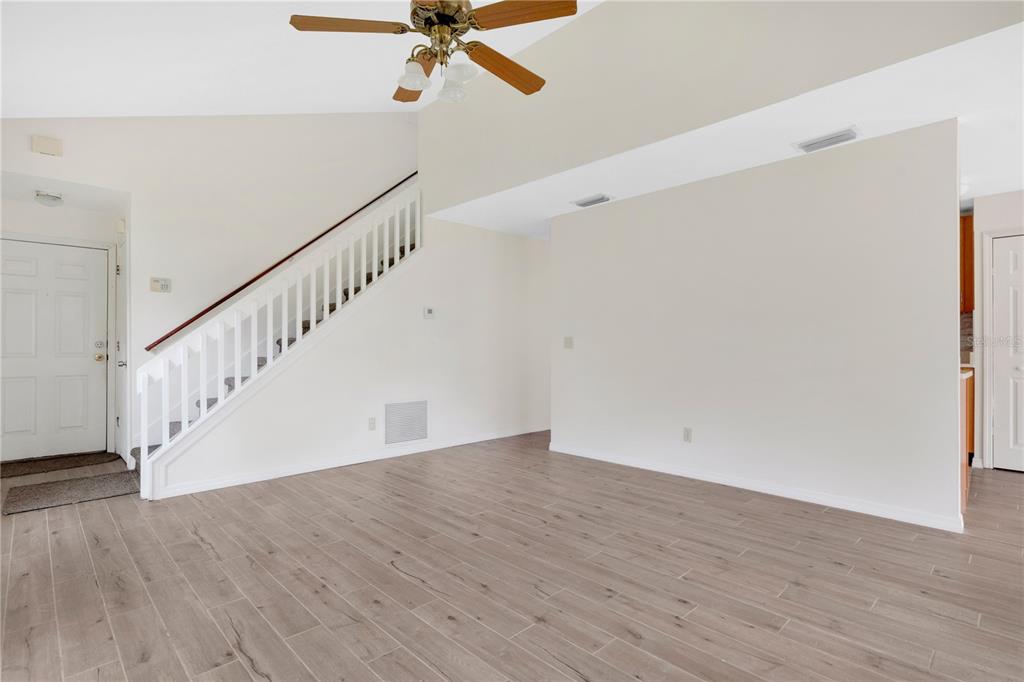 An interior view of a living room with light wood-look flooring and a staircase — 11842 ATLIN DRIVE, ORLANDO, FL