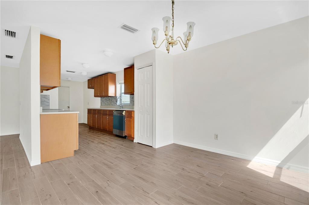 A kitchen with wood cabinets and light wood-look flooring opens into a dining area — 11842 ATLIN DRIVE, ORLANDO, FL