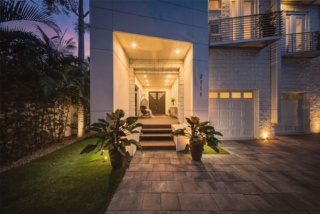 A modern house exterior features a recessed entryway with steps, a garage, and landscaping — 2711 W TRILBY AVENUE, TAMPA, FL