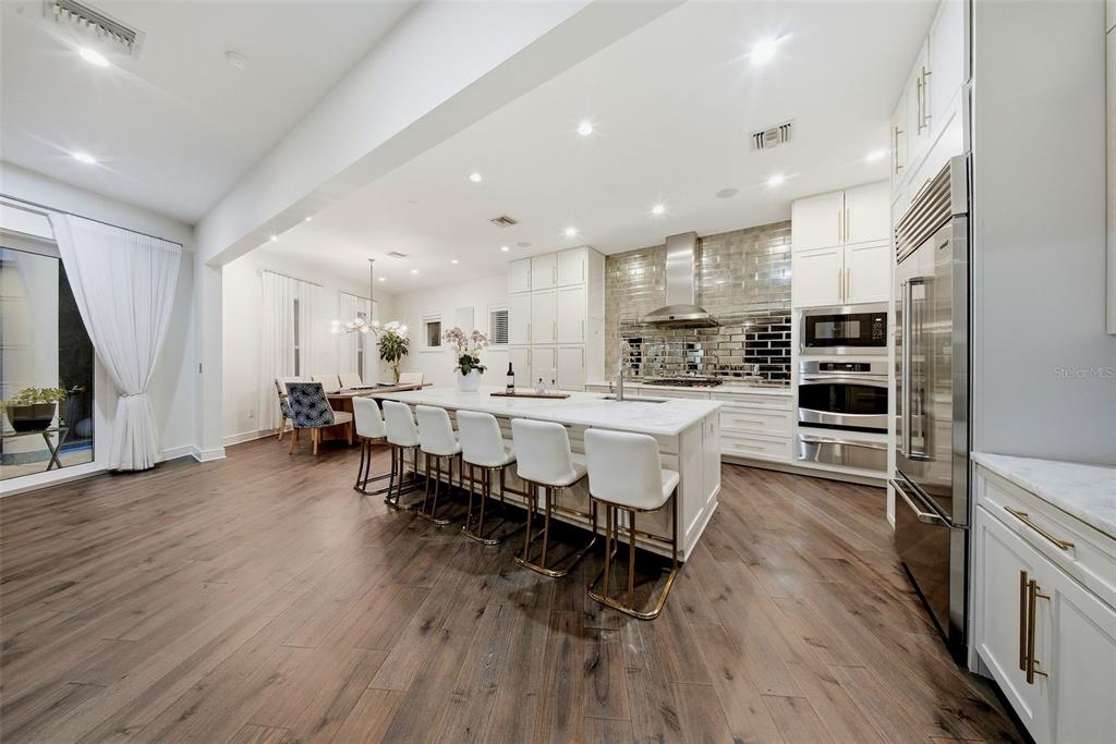 A modern kitchen features a large white marble island with bar stools and hardwood floors — 2711 W TRILBY AVENUE, TAMPA, FL