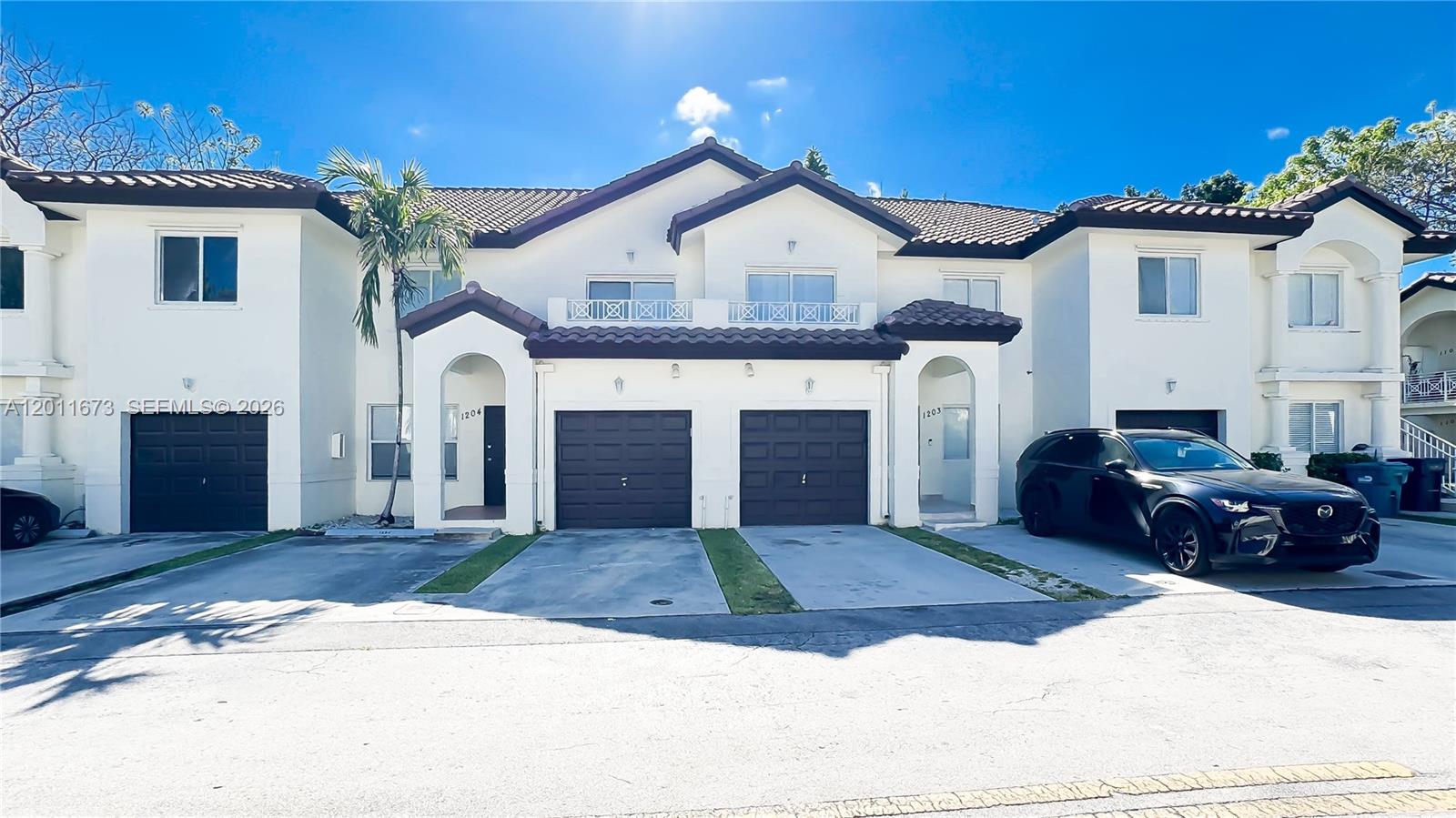 A row of two-story townhouses with brown garage doors and white stucco exteriors — 8902 NW 109th Ct # 1204, Doral FL 33178, DORAL, FL