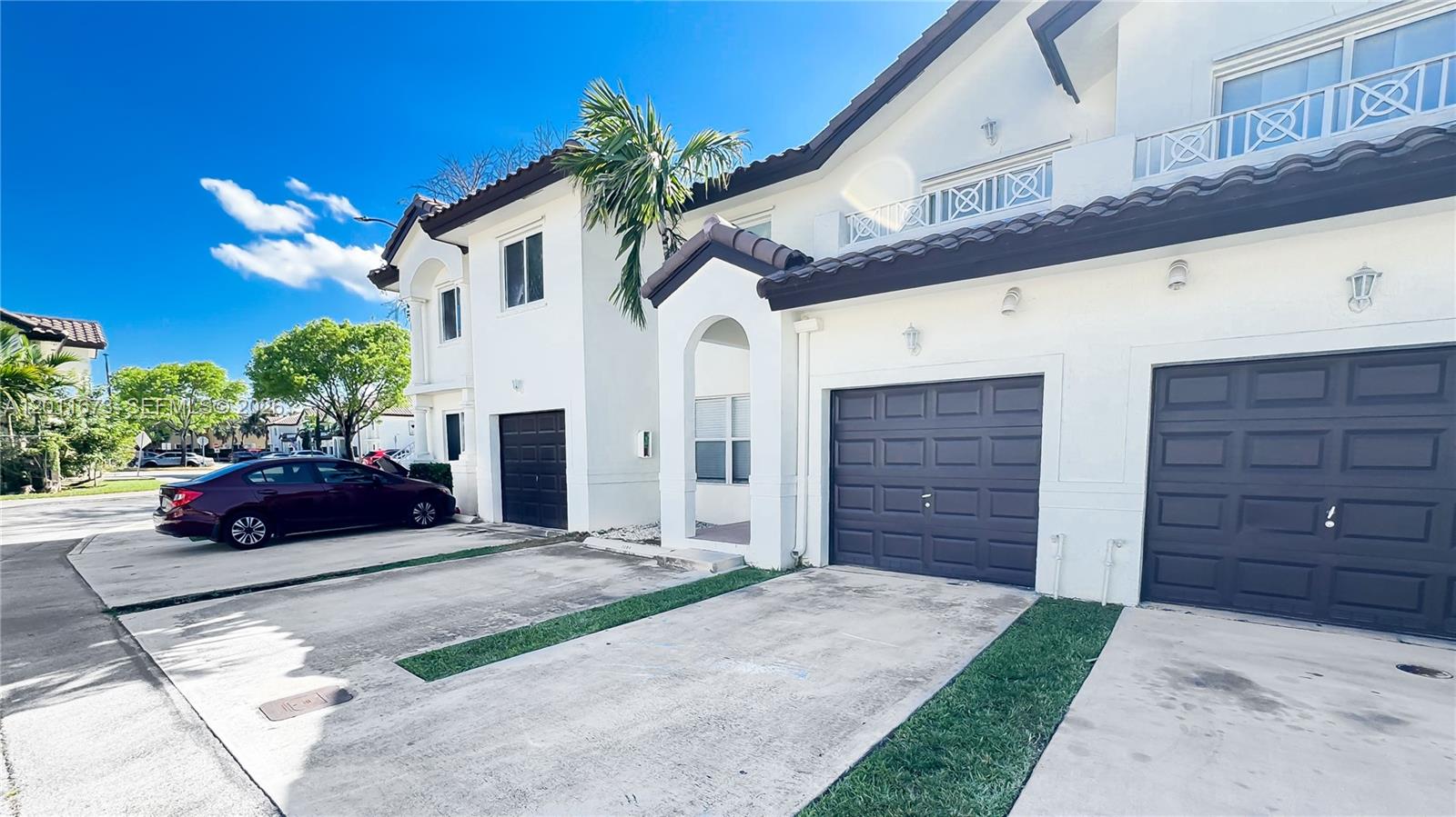 The exterior of a two-story townhouse features white stucco walls, dark garage doors, and tile roofs — 8902 NW 109th Ct # 1204, Doral FL 33178, DORAL, FL