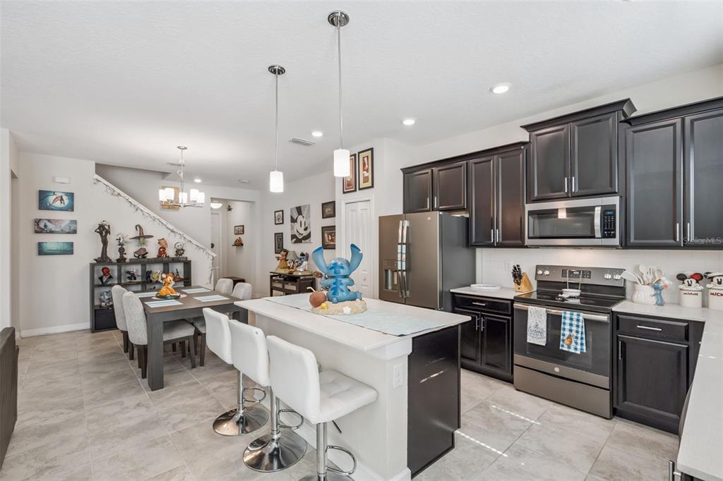 A kitchen with dark cabinets, a white island, and an adjacent dining area with stairs — 2931 SENTENCE STREET, KISSIMMEE, FL