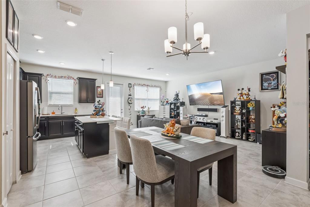 An open-concept kitchen, dining area, and living room with dark cabinetry and tile flooring — 2931 SENTENCE STREET, KISSIMMEE, FL