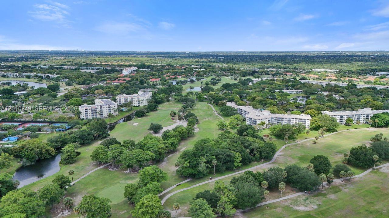 An aerial view shows a golf course surrounded by apartment buildings and lush green trees — 575 Oaks Ln # 508, Pompano Beach FL 33069, POMPANO BEACH, FL