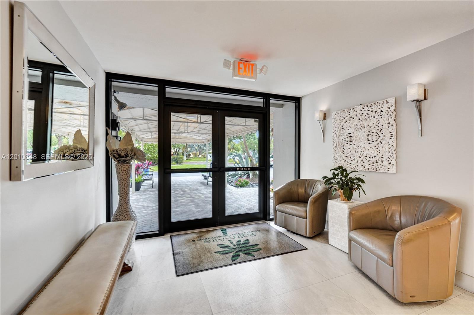 A lobby entrance features glass double doors, two tan armchairs, and a decorative wall panel — 575 Oaks Ln # 508, Pompano Beach FL 33069, POMPANO BEACH, FL