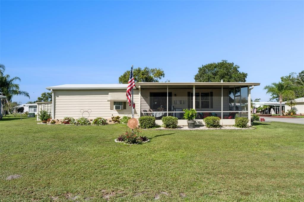 A single-story mobile home with a screened-in porch and an American flag in the yard — 301 LAKEVIEW DRIVE, OSTEEN, FL