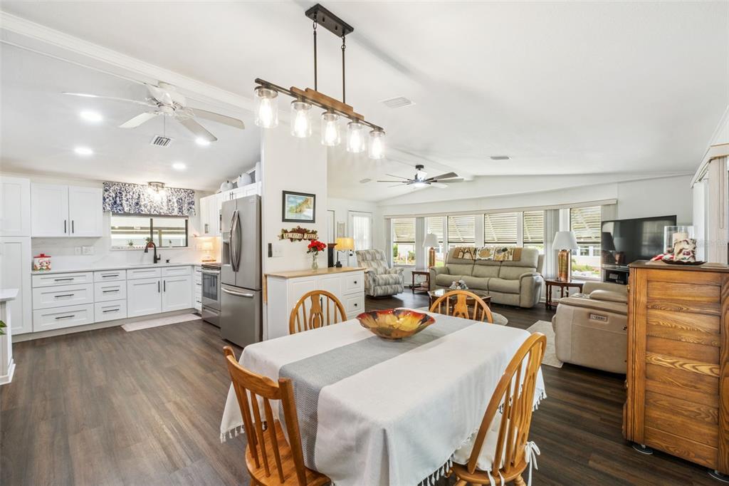 An open-concept kitchen, dining area, and living room with white cabinets and wood-look flooring — 301 LAKEVIEW DRIVE, OSTEEN, FL