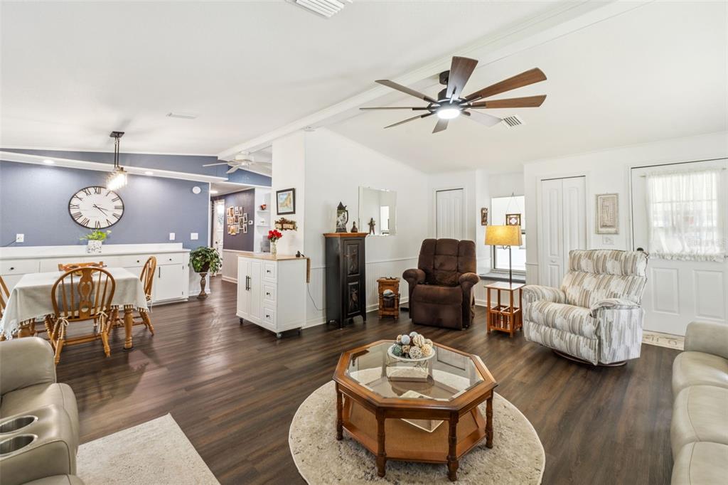 A living room and dining area feature dark wood floors, white walls, and a ceiling fan — 301 LAKEVIEW DRIVE, OSTEEN, FL