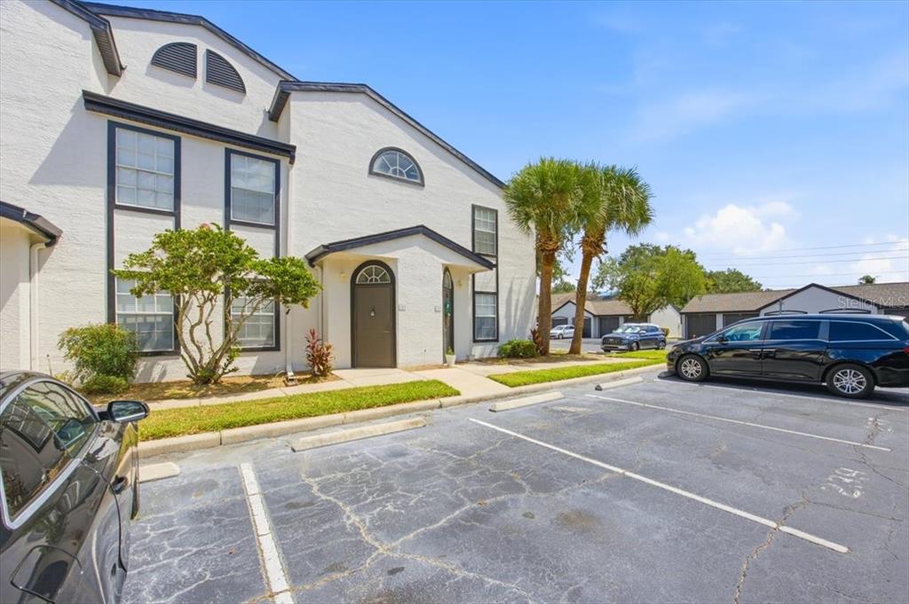 A two-story stucco townhouse exterior features dark trim, arched windows, and a parking lot — 1612 COLUMBIA ARMS CIRCLE UNIT 237, KISSIMMEE, FL