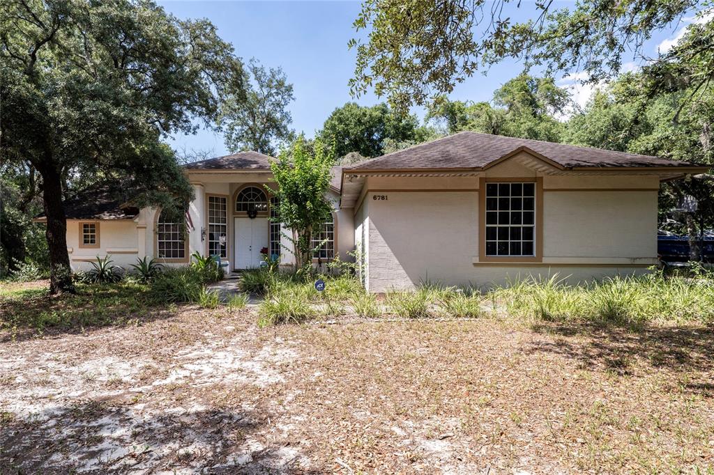 A single-story house with a beige stucco exterior and a dark shingled roof — 6781 W LIVINGSTON STREET, ORLANDO, FL