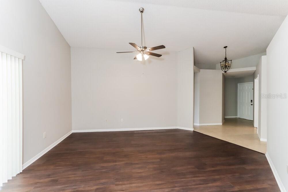 An empty living room features dark wood-look flooring, light gray walls, and a ceiling fan — 1846 TWISTING LANE, WESLEY CHAPEL, FL
