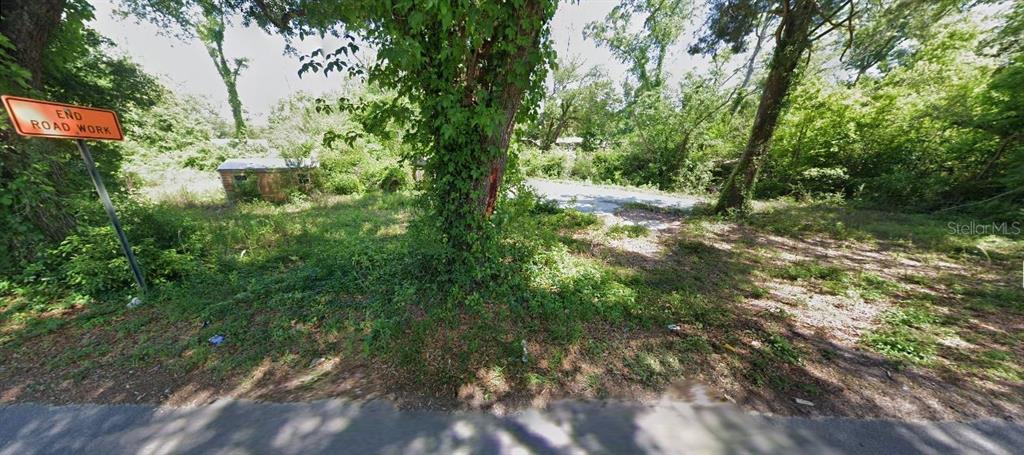 A wooded, overgrown lot features an "End Road Work" sign and a small, weathered shed — 2916 MILTON AVENUE, MARIANNA, FL